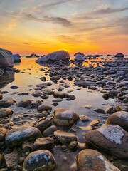 Fototapeta na wymiar Tranquil Scene of a Rocky Seashore at Sunset with Vibrant Colors Painting the Sky and Reflecting on the Water, Creating a Stunning and Serene View of Natures Beauty.