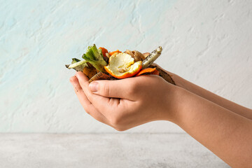 Female hands holding organic waste with soil on white grunge background. Compost recycling concept