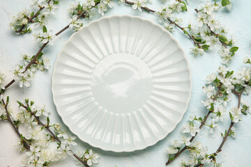 Beautiful table setting with blossoming branches on light blue background
