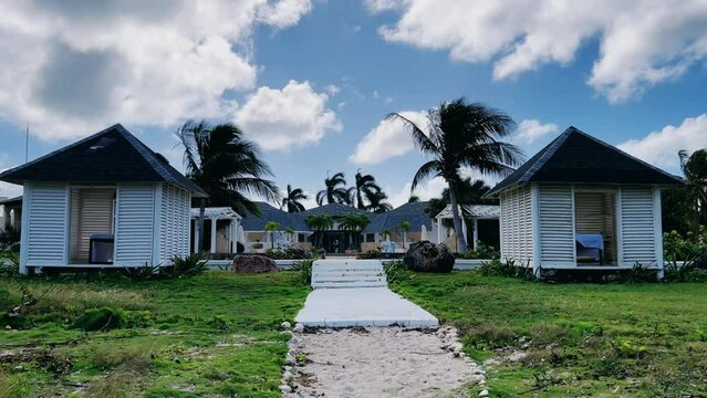 Varadero, Cuba, 03.12.2023. Coconut palm leaves sway in the wind on the territory of a hotel with white buildings in Cuba. Vacation on the Caribbean coast on Liberty Island. 4К