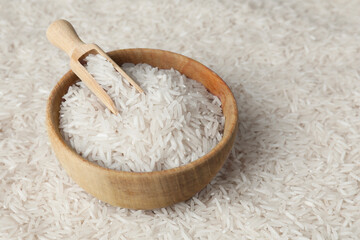 Fototapeta na wymiar Raw basmati rice, bowl and scoop as background, closeup