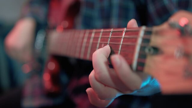 Guitarist's Fingers on Red Electric Guitar Fretboard