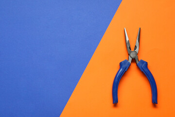 Needle nose pliers on color background, top view. Space for text