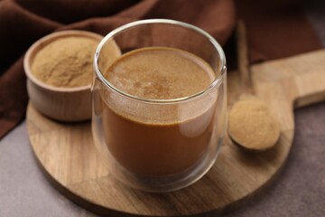 Soluble fiber with water in glass, powder and spoon on brown table, closeup