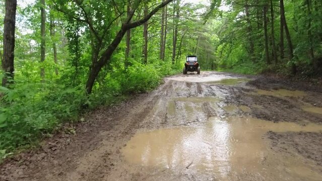 4 seater UTV driving through a forest across deep mud summer time