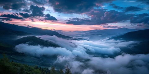 Fototapeta premium The sky is a beautiful mix of pink and blue hues, with clouds covering the mountains in the distance. The misty atmosphere adds a sense of mystery and tranquility to the scene