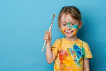 Girl with paint on face holding a paintbrush.