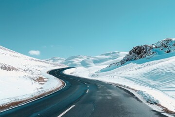 Winding road through snow-covered mountains under a clear blue sky.