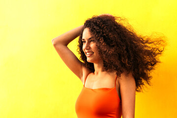 beautiful afro woman looking aside portrait leaning on a yellow wall. side view