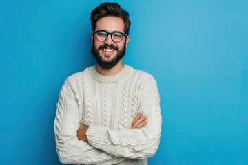 Young handsome man with beard wearing casual sweater and glasses over blue background happy face smiling with crossed arms looking at the camera. Positive person - generative ai - obrazy, fototapety, plakaty