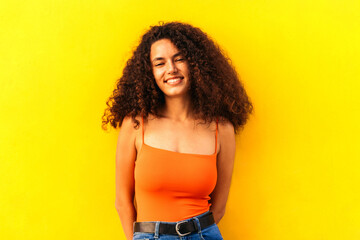 beautiful afro woman portrait leaning on a yellow wall