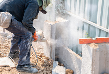 Worker cutting concrete pile column by electric cutting machine.