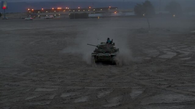 Man in small tank having battle with another tank in dirt field - drone shot