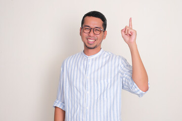 Adult Asian man smiling at the camera with one hand pointing up