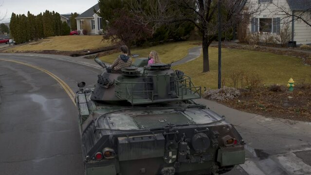 Teens driving tank through neighborhood street