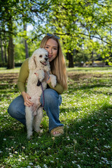 Cute girl with her pet dog posing in sunny park in spring 