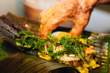 hand of an elderly woman preparing the ingredients of a Colombian tamale on some banana leaves