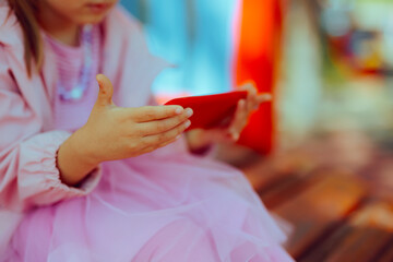 Child Using a Smartphone at the Playground instead of Playing. Toddler girl being captivated and...
