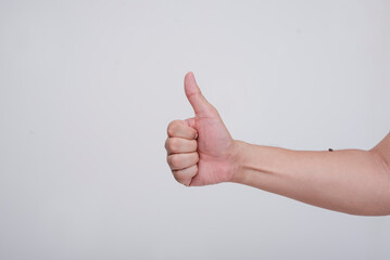 Close-up of a man's hand making a thumbs up sign, depicting approval or agreement, isolated on a...
