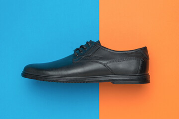 Men's leather shoe on a blue-orange background.