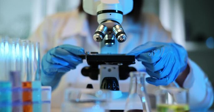 Researcher places sample under microscope in laboratory