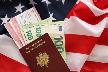 French passport and euro money with airline tickets on United States national flag background close...