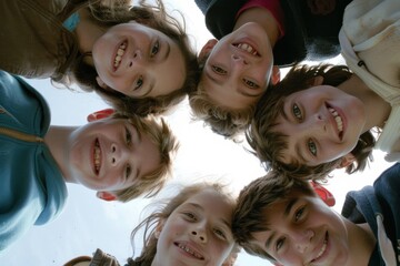 A group of happy, cheerful and cute children played together and had a great time. Group portrait of happy children huddled together, looking down at the camera and smiling. Low angle, view from below