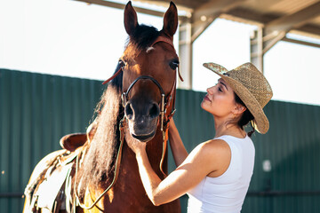 Woman taking care of his brown horse in an equestrian center