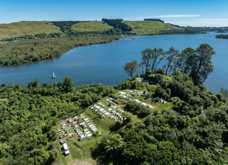 Aerial: Cemetery, Sailboat and forest in the calm Lake Rotoiti, Rotorua, Bay of Plenty, New Zealand.