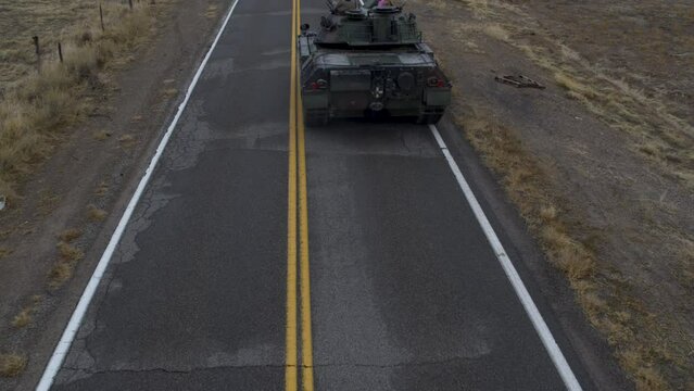 Large, old tank traveling down desert highway - drone shot