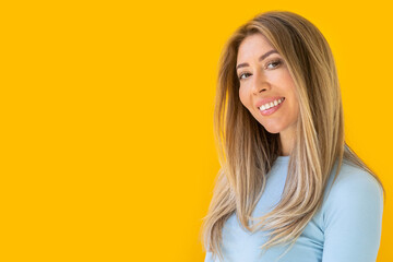 Portrait of a young Caucasian woman with pleasant smile isolated on yellow wall with copy space.  - obrazy, fototapety, plakaty