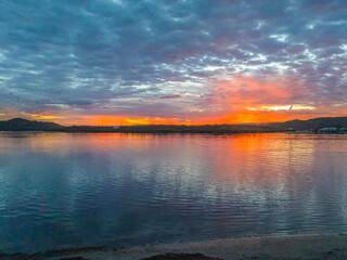 Sunrise over the bay water with clouds and birds in the sky