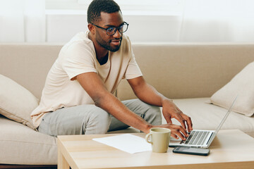 African American Man Working on Laptop in Modern Apartment, Smiling