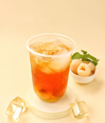 Lychee tea on plastic cup with ice cube and lychee fruit