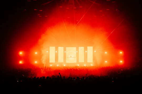 DJ performing infront of a large crowd with a large production of lasers and lights