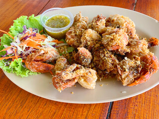 Fried soft shell crab with garlic and pepper with seafood dipping sauce on a brown plastic plate