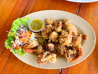 Fried soft shell crab with garlic and pepper with seafood dipping sauce on a brown plastic plate