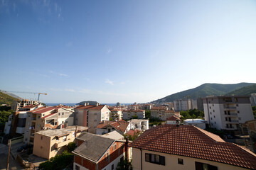 Fototapeta na wymiar Red roofs of apartment buildings at the foot of the mountains near the sea. Budva, Montenegro