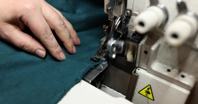 Seamstress uses overlock machine to secure fabric edges