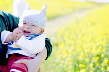 菜の花畑のキュートな帽子を被った赤ちゃん /Baby in a cute hat in a field of rape...
