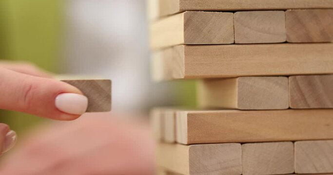 Woman removes wooden block playing popular jigsaw puzzle