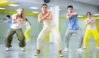 Dancer boys and girls showing different tricks and movements while dancing in studio, flexible and sportive female on the floor