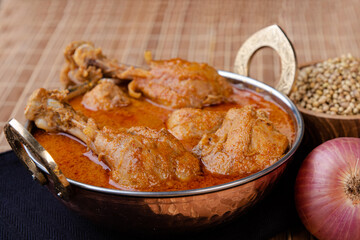 Goan, malvani and konkani style chicken gravy presented in a copper vessel with chicken leg pieces.