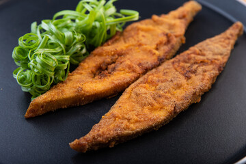 Paplet or pomfret fish fry malvani, konkani and goan style on a black background with garish.