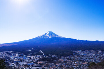 Look pass village and city at Mount Fuji world famous tourist attractions. Beautiful mountain with snow and white fog cover on top with bright blue sky, bright is background.