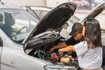 Male and female team of mechanics repairing a car