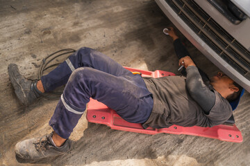Mechanic leaning on platform repairing a car