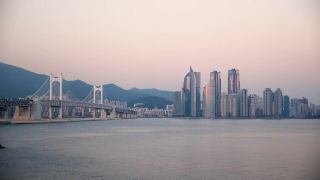 Sunset view of Gwangan or Diamond bridge in Busan with skyscrapers in Haeundae, South Korea. High quality 4k footage