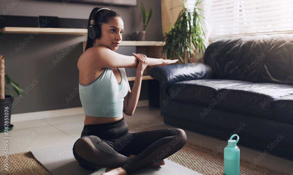 Wall mural Fitness, stretching and woman on mat with headphones for cardio, exercise or podcast in workout. Female person, thinking and training with music at home for streaming, warm up and self care on floor