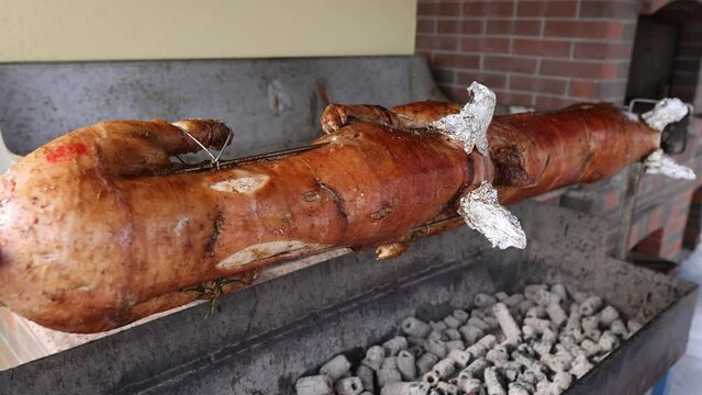 Details with suckling pigs roasting over burning coals.